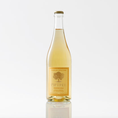 Piptree Crimson Gold sparkling apple cider in a clear 750ml bottle with a gold label, pale golden juice inside.