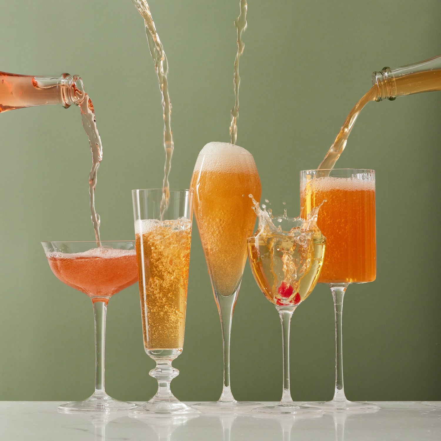 All three Piptree sparkling apple ciders pouring into different glasses against a sage green backdrop.